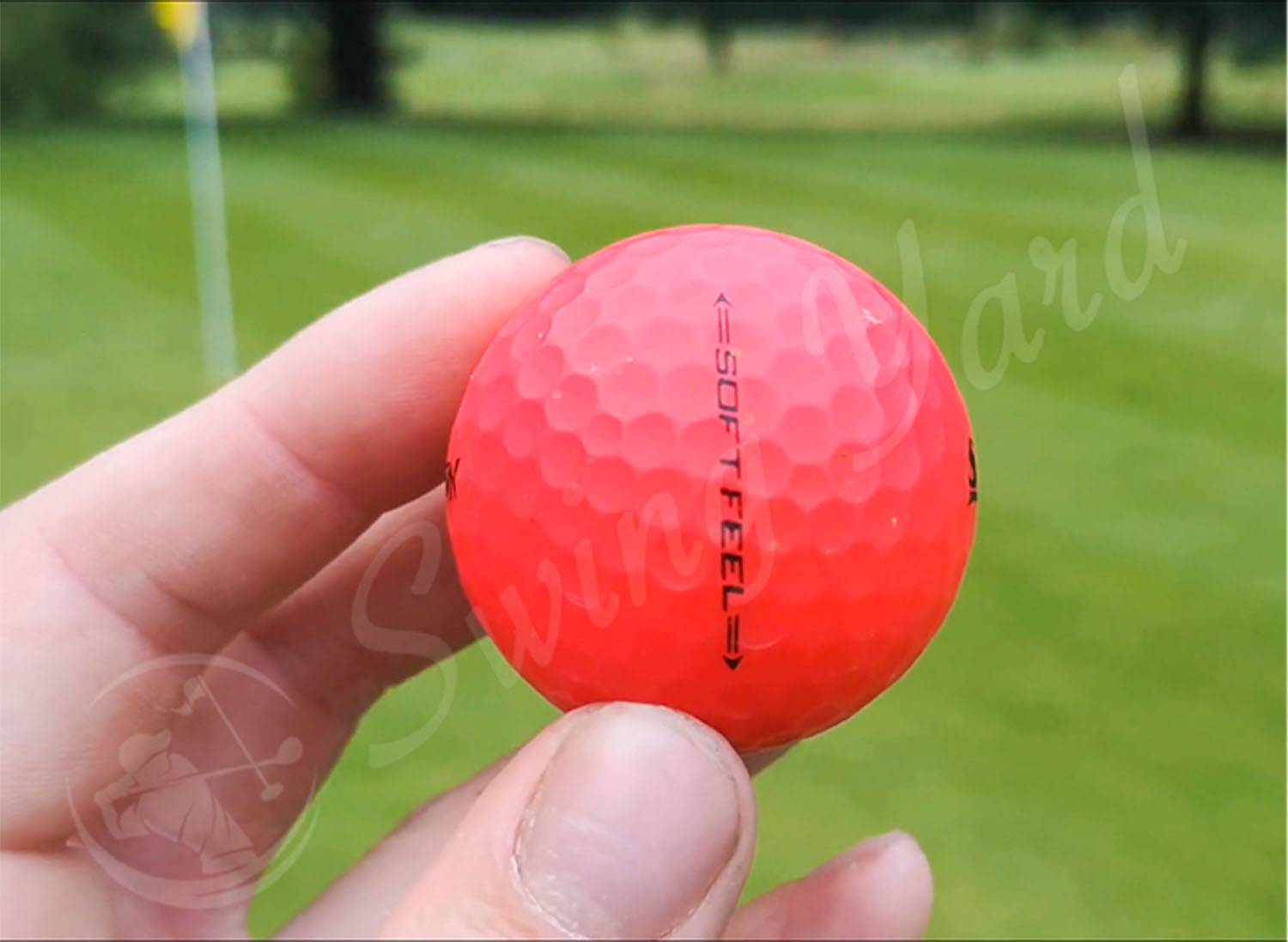 A red Srixon Soft Feel ball in my hand at the golf course