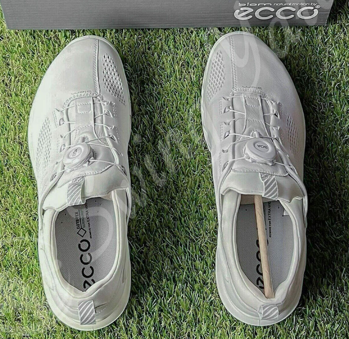 A white pair of ECCO men biom hybrid 3 boa hydromax water resistant winter golf shoes in the grass