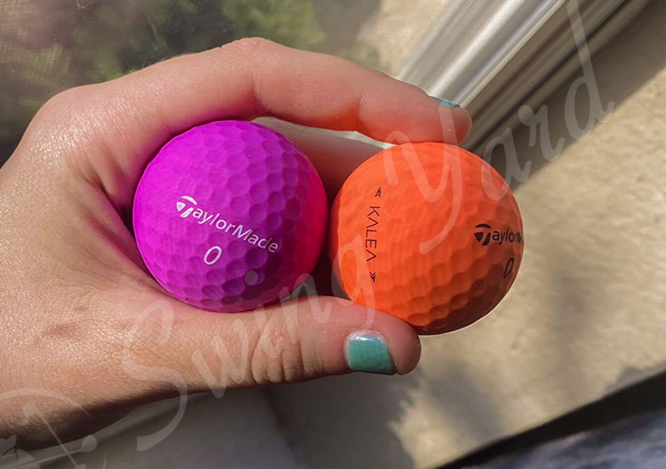 Me holding orange and violet TaylorMade Kalea balls for testing at the golf course