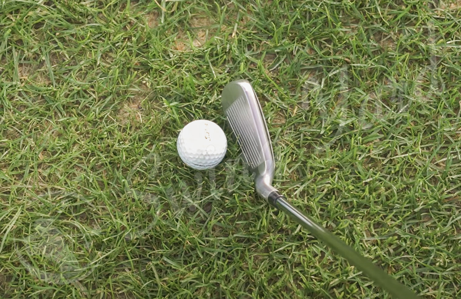 A TaylorMade Stealth HD Women Iron hitting a golf ball in the grass