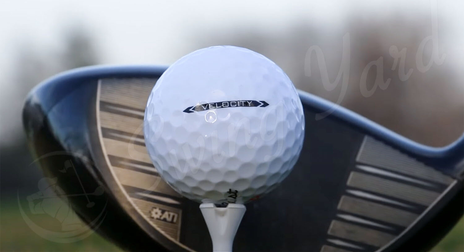 A close view of Titleist Velocity ball with golf tee and a driver