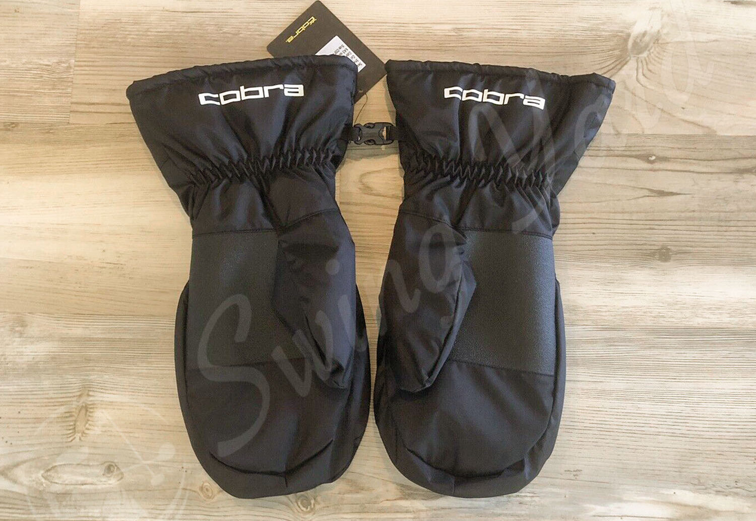 A backside view of Cobra golf winter mitts on the floor