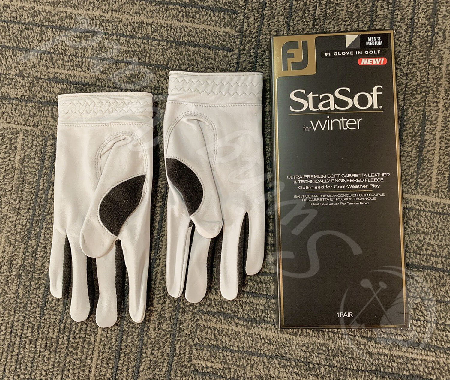 A pair of white FootJoy StaSof winter gloves on the floor