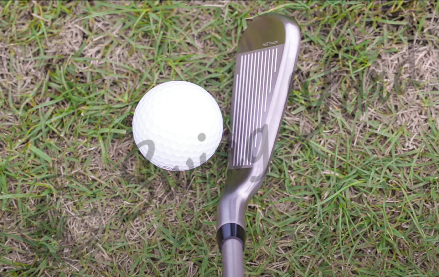 A facial view of Cobra AeroJet Iron hitting a golf ball in the grass