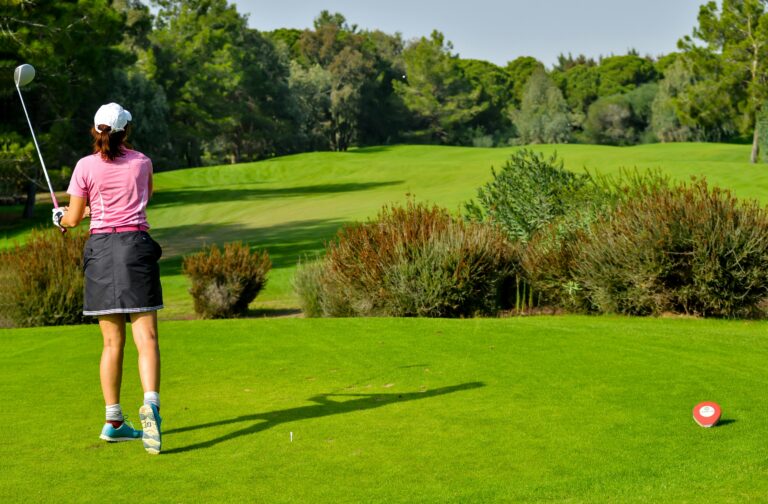 A women golfer swinging through the golf ball showing the best golf tips for women