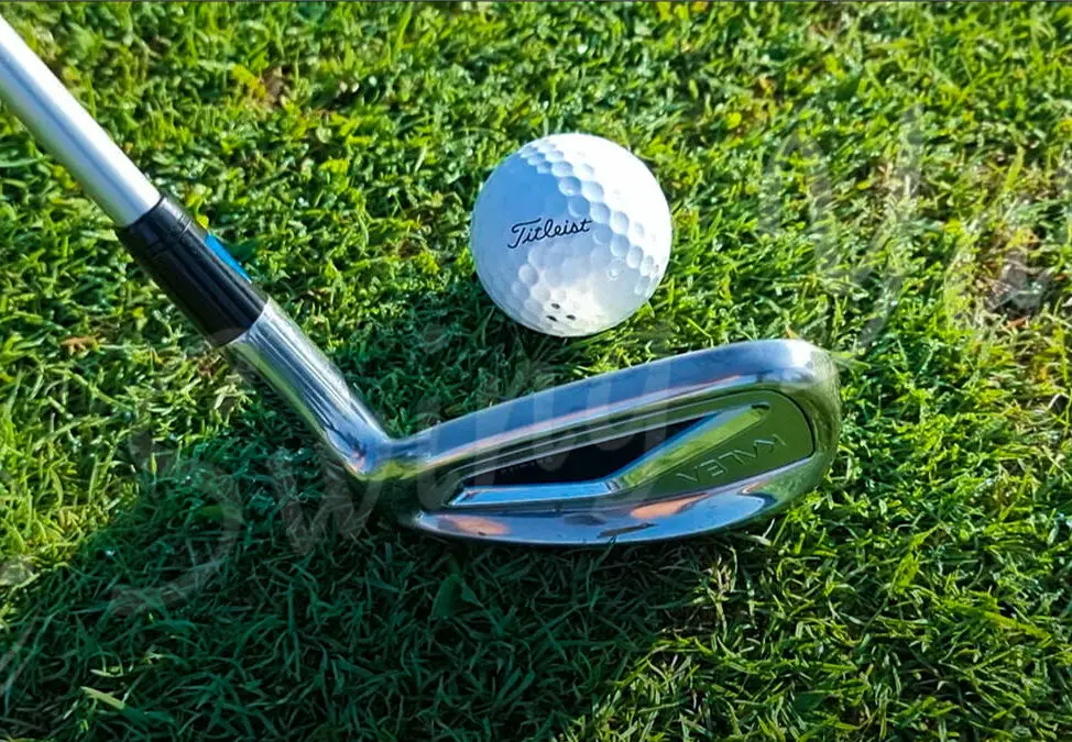 A TaylorMade Kalea Premier Iron hitting the golf ball in the grass