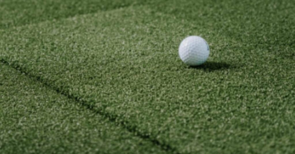 Golf ball on artificial turf hitting mat for home golf simulator practice and training