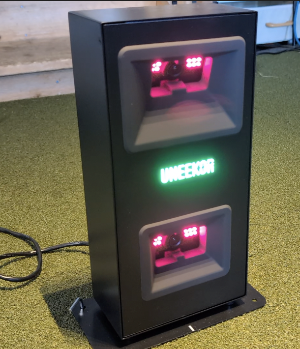 The Uneekor EYE MINI LITE golf launch monitor is turned on and detecting a golf ball in the hitting area.