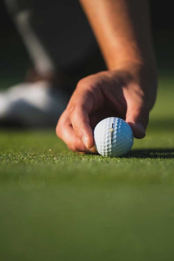 golfer aligning his golf ball on the putting green