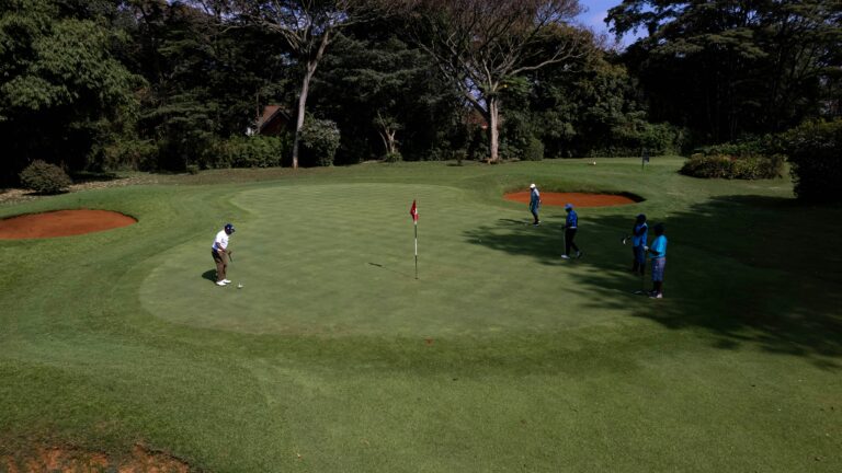a group of golfers reading and hitting putts on the golf course