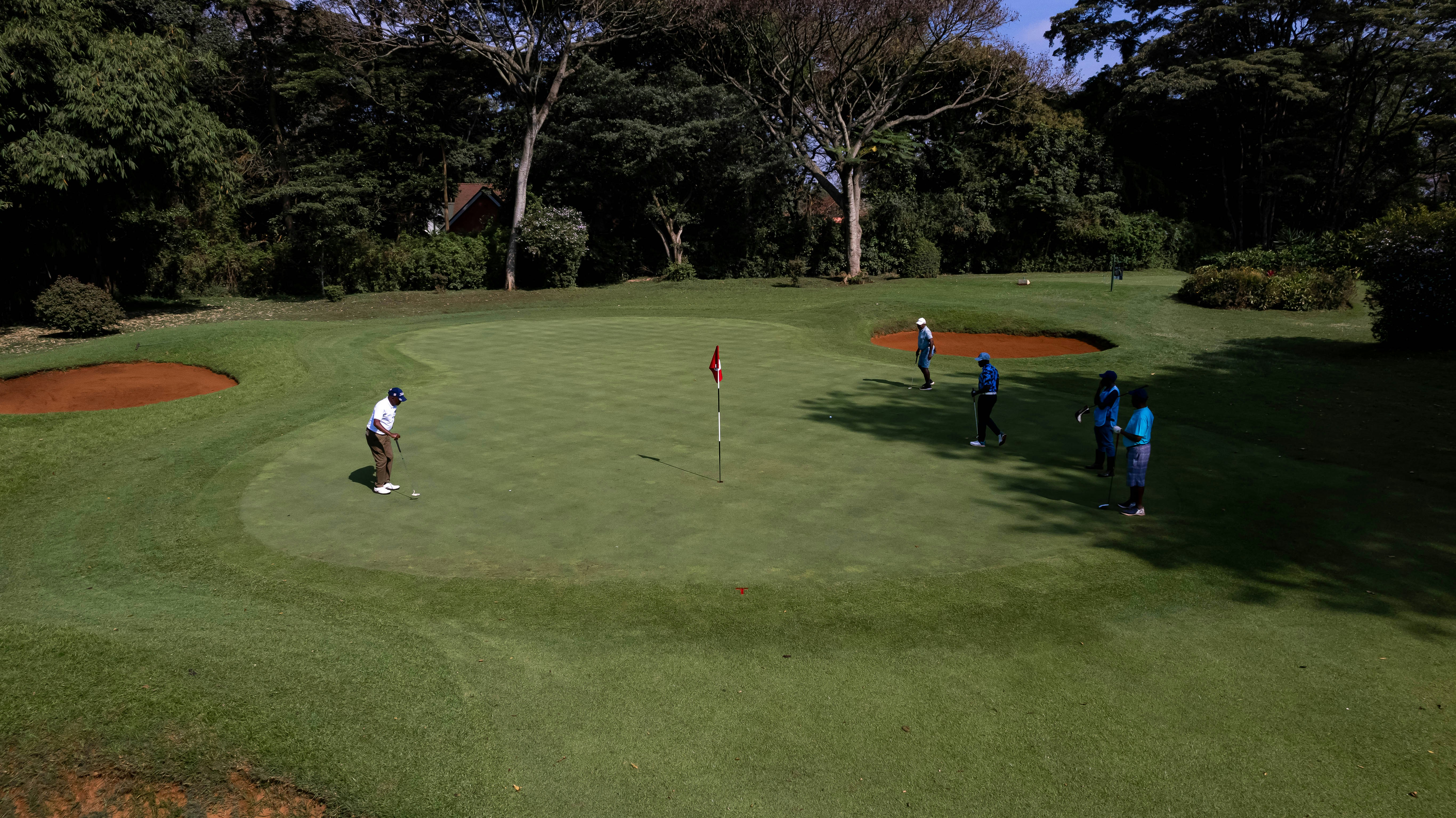 a group of golfers reading and hitting putts on the golf course