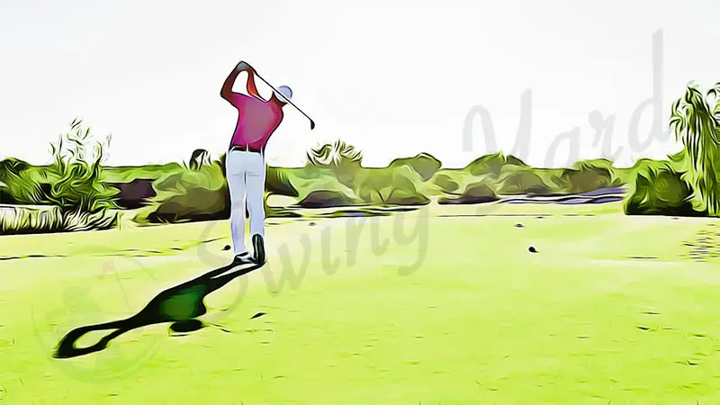 a guy hitting a golf driver in the sunset